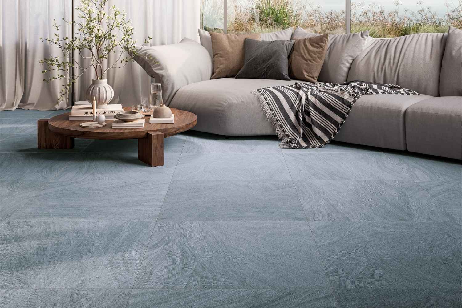 Refin Ink Wavy als Bodenfliese in Blau- und Grautönen mit feiner künstlerischer Linienstruktur und sanft geschwungenem Muster, verlegt in einem modernen Wohnzimmer