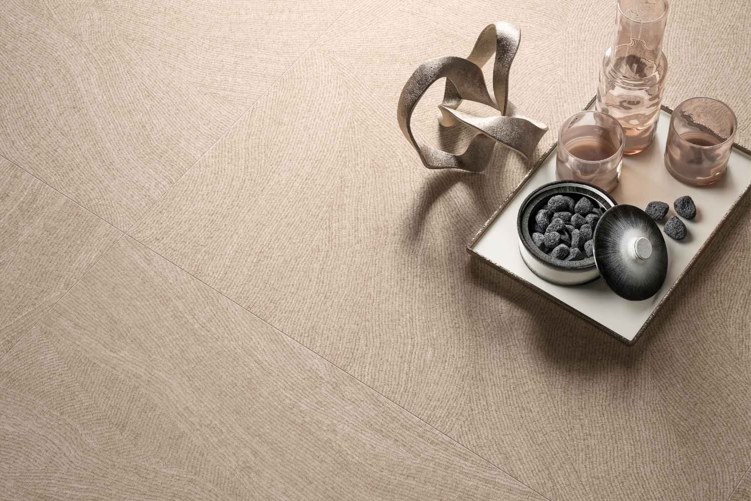 Detailansicht der Refin Ink Cozy Bodenfliese in warmer Beige- und Taupe-Farbgebung mit feiner textilartiger Struktur, sanften Linien und moderner Designoptik