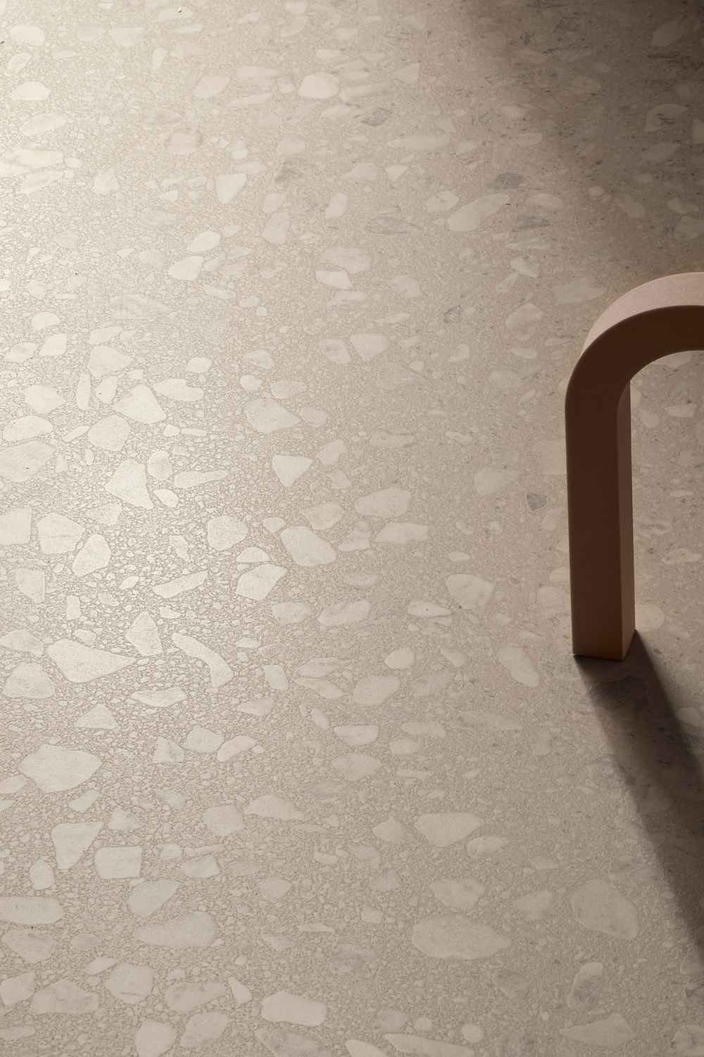 Nahaufnahme der Sant Agostino Glow Sand seidenmatt mit warmer beige-greiger Grundfarbe, heller Steinzeichnung und sanftem Lichtspiel auf der Oberfläche