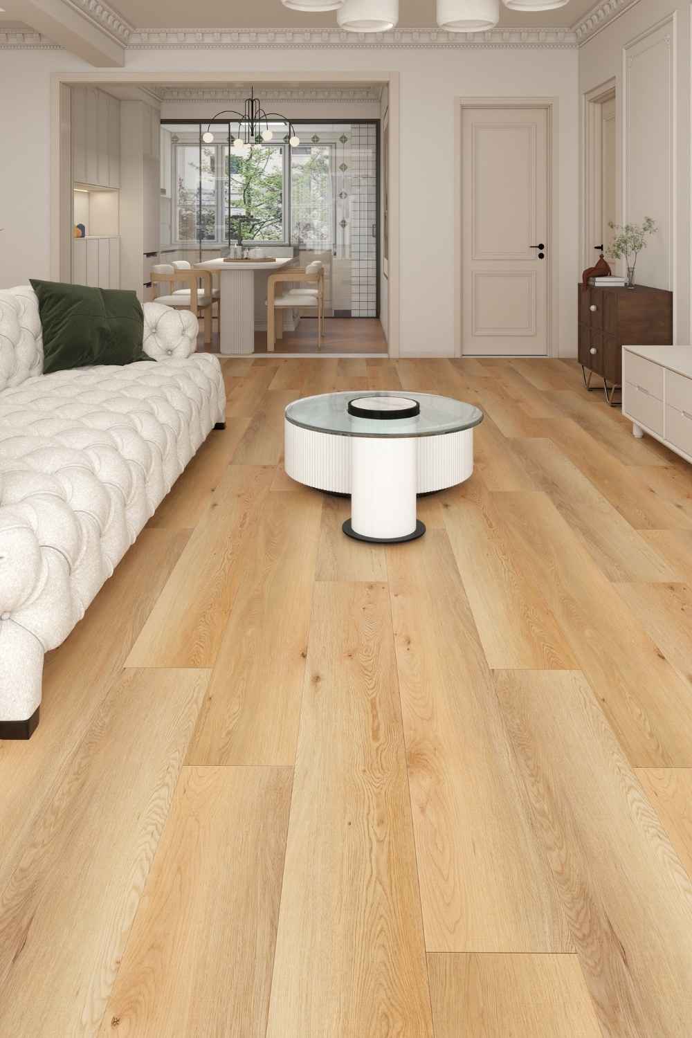 SPC Vinylboden Ana Cerezo mit langen Dielen in honigbrauner Holzoptik und sichtbaren Astzeichnungen im hellen Wohnzimmer mit weißem Sofa, rundem Couchtisch und angrenzendem Essbereich.