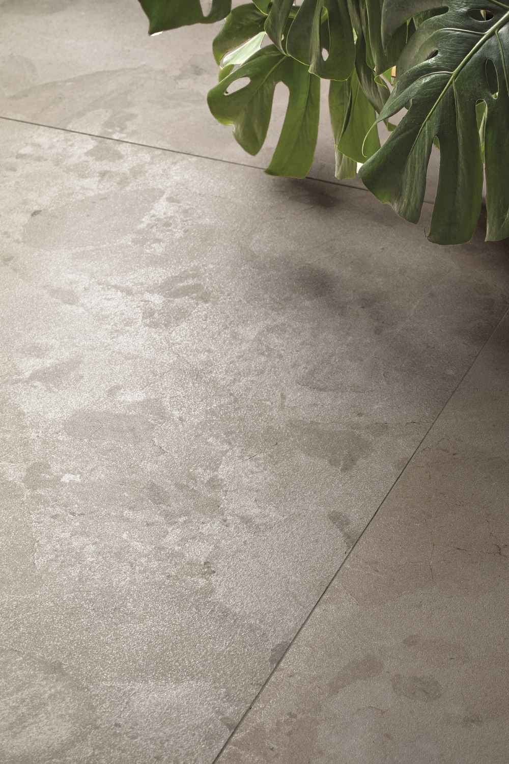 Detailansicht der Refin Moon Twilight Bodenfliese in warmem Mittelgrau mit mineralischer Struktur, wolkigen Schattierungen und leicht schimmernder Oberfläche in moderner Stein- und Terrazzooptik
