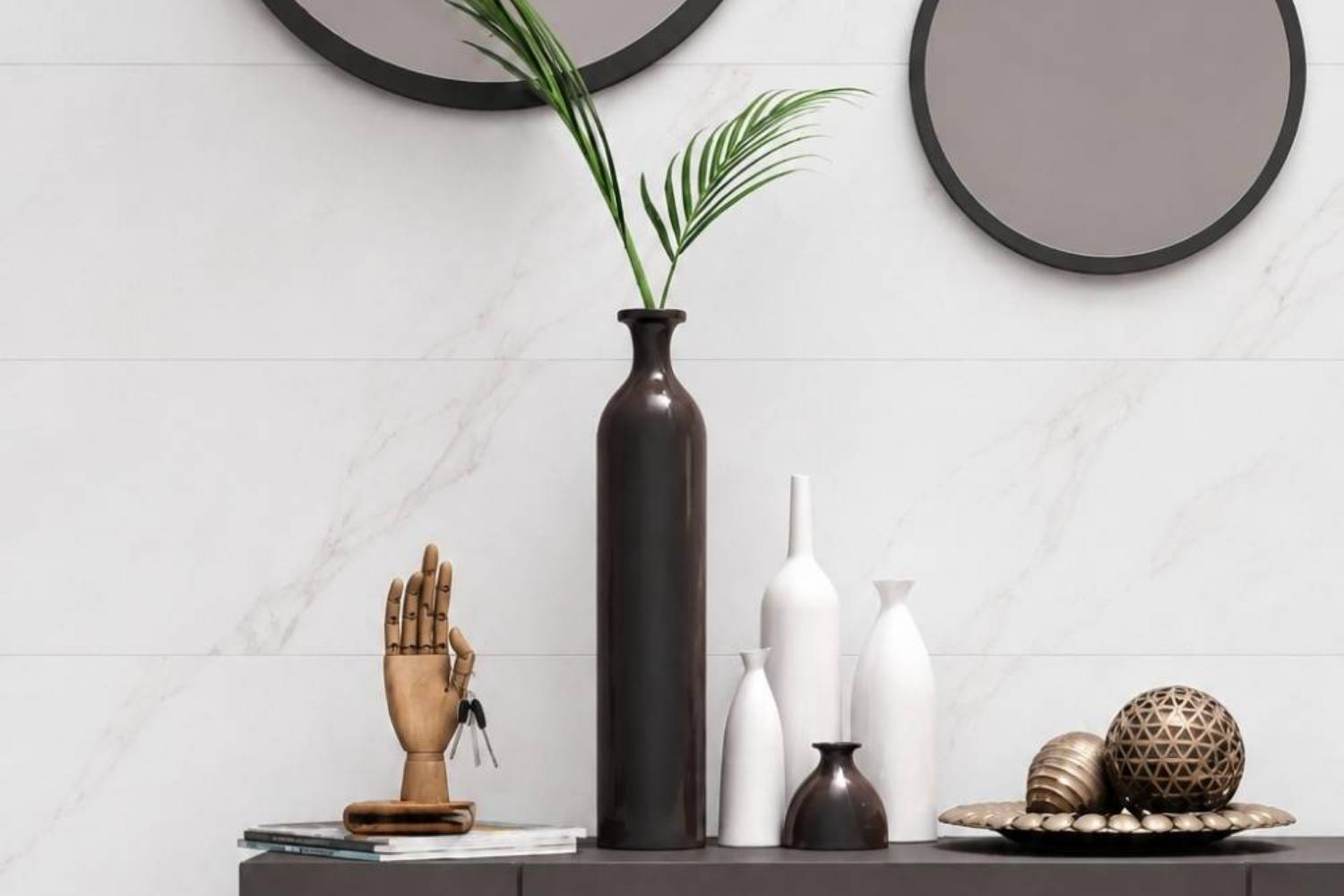 Palatina weiß matt 30x90 cm als Wandfliese in heller Marmoroptik mit Tisch auf dem eine Vase und Deko steht