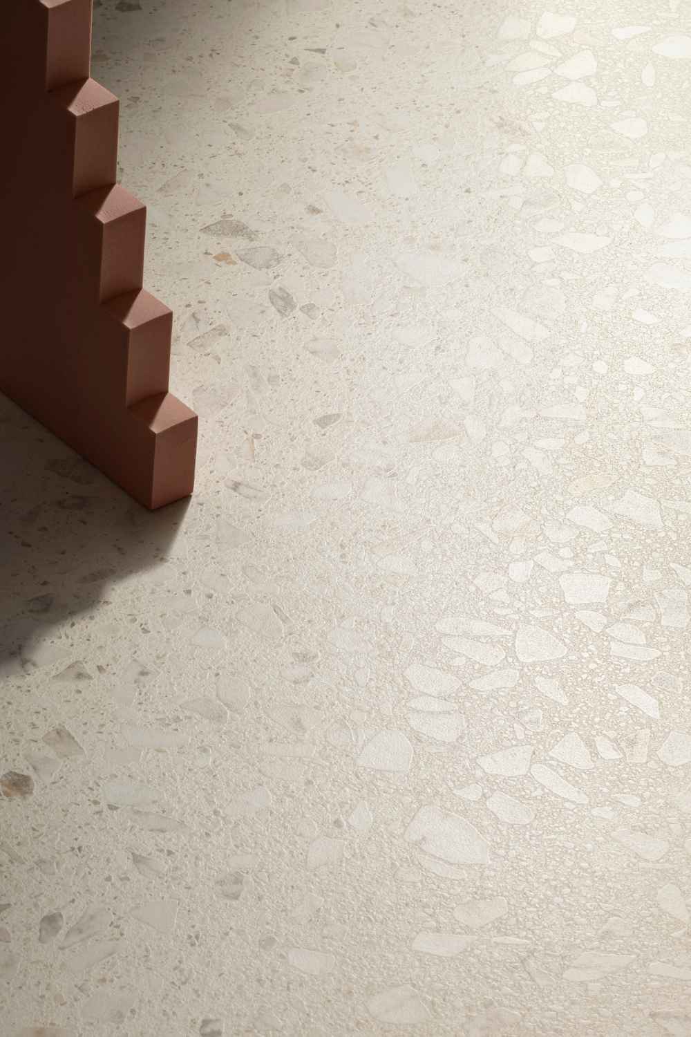 Detailaufnahme der Sant Agostino Glow Ivory seidenmatt mit hellem Elfenbeinton, feiner Terrazzo-Struktur und sanftem Lichtspiel auf der Oberfläche