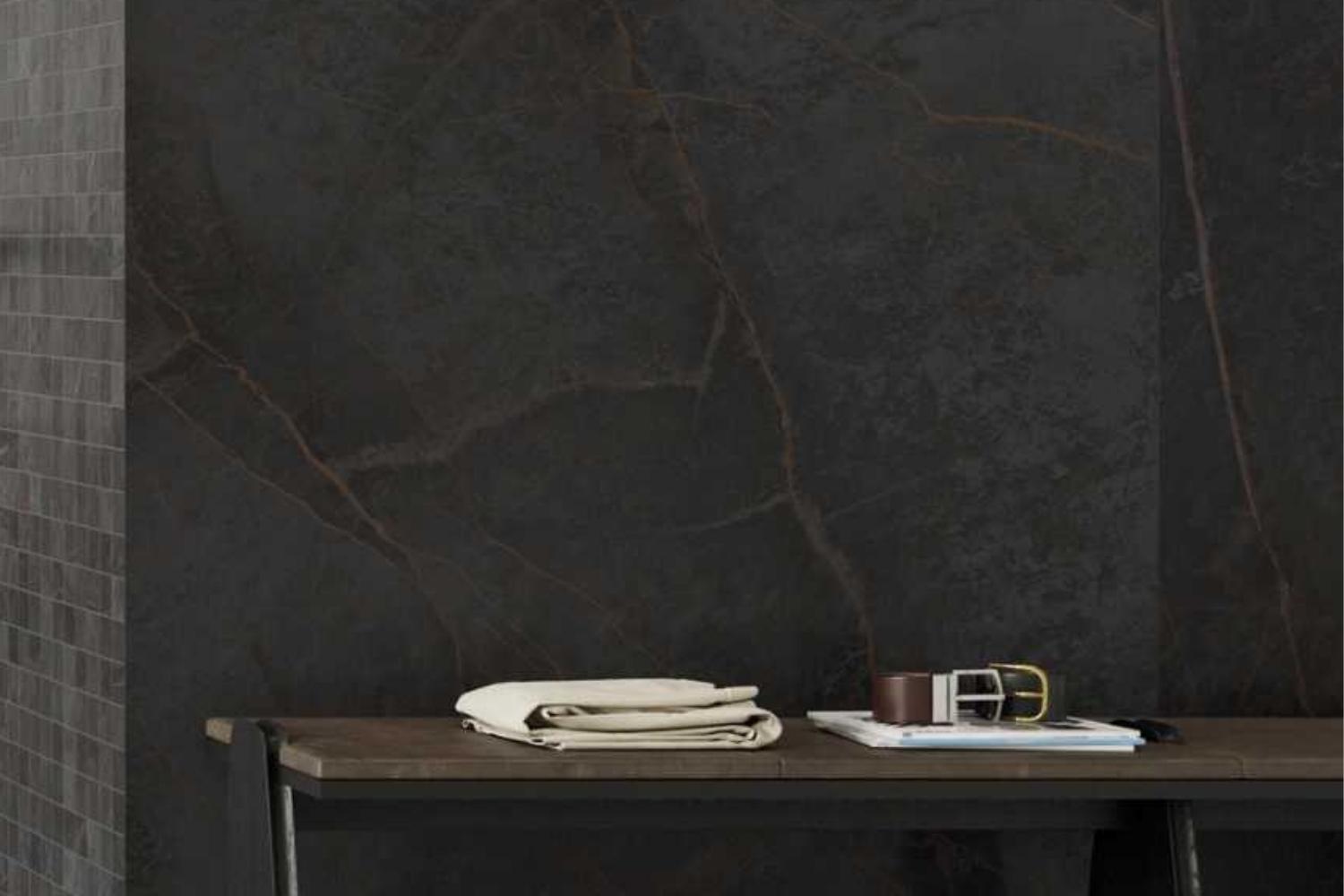 Monocibec On Stage Adelphi als dunkle Wandfliese in markanter Marmoroptik mit feinen warmen Aderungen, kombiniert mit moderner Einrichtung und edlen Wohnaccessoires