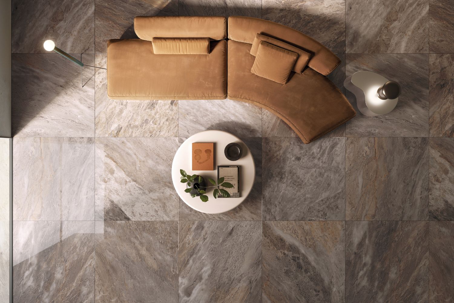 Refin Prestigio Kaleidos Agata als matte Bodenfliese in ausdrucksstarker Breccia-Marmoroptik mit warmen Braun-, Grau- und Beigetönen, gezeigt in einem modernen Wohnbereich mit geschwungenem Sofa