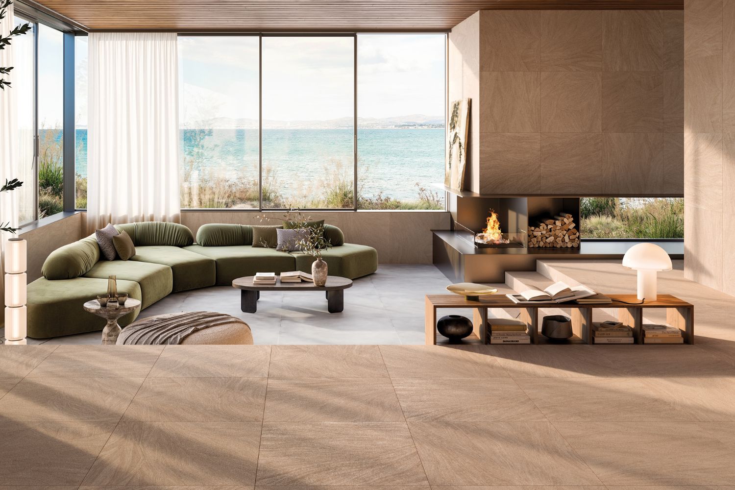 Refin Ink Blush als großformatige Boden- und Wandfliese in warmer Beige- und Rosé-Taupe-Farbgebung mit feiner textilartiger Steinstruktur, verlegt in einem modernen Wohnzimmer mit großen Fensterflächen und Kamin